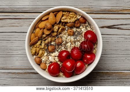 Bowl Of Oat Granola With Freshberries And Nuts On White Wooden Board For Healthy Breakfast