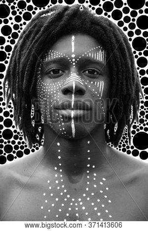 Portrait of young african man with dreadlocks and traditional face paint looking straight into the camera