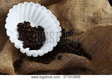 An Image Of Several White Basket Style Coffee Filers And Dark Roasted Coffee Beans.