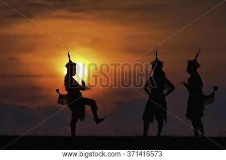 The Black Silhouette Of Three Manohra Actors Dancing In The Park In The Evening.