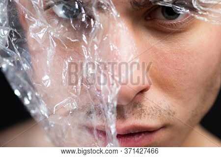 Guy Handsome Face Cellophane Mask. Trash Concept. Plastic Pollution. Man Transparent Piece Of Plasti