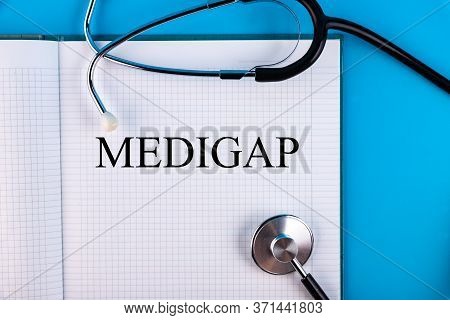 Medigap Text Written In A Notebook Lying On A Desk And A Stethoscope. Medical Concept.
