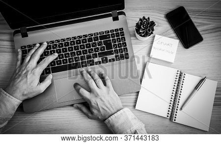 Male Hands Working On Modern Laptop. Working At Home On The Desk With Laptop, Agenda, Pen, Post It A