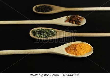Four Wooden Spoons With Saffron, Oregano, Chillies And Black Pepper