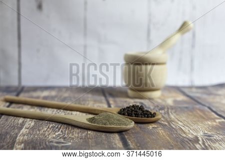 Two Wooden Spoons With Black Peppercorns