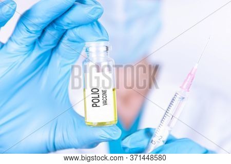 Text Polio Vaccine Of Is Written On A Bottle With The Background Of A Doctor With A Syringe In A Med