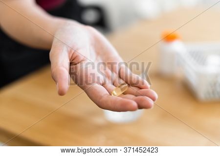 Close Up Womans Hands With Supplements Pills And Glass Of Water. Self Health Care With Preventive Me