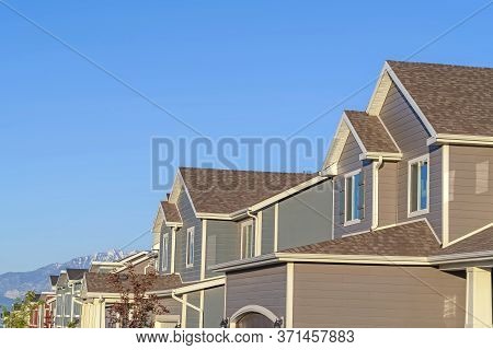 Row Of Houses In A Suburb Neighborhood With Mountain And Blue Sky Background