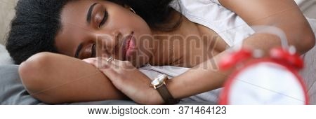Young Woman Is Sleeping An Alarm Clock Is On Table. Beautiful Girl Takes Every Opportunity To Recove