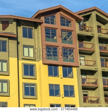 Square Residential Building With Multi Color Wall And Small Balconies Against Blue Sky