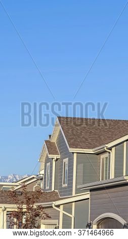 Vertical Crop Row Of Houses In A Suburb Neighborhood With Mountain And Blue Sky Background
