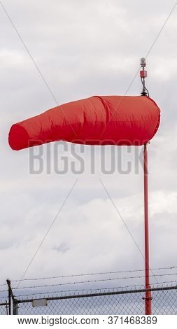 Vertical Red Wind Sock At An Airport Blowing In The Wind