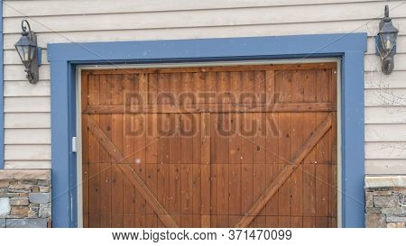 Panorama Brown Wood Garage Door With Blue Frame Flaned By Wall Mounted Vintage Lanterns