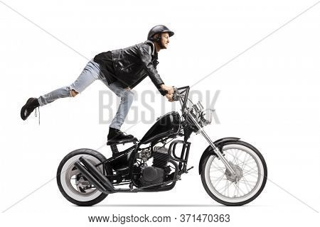 Daredevil biker standing on the seat and riding a chopper motorbike isolated on white background