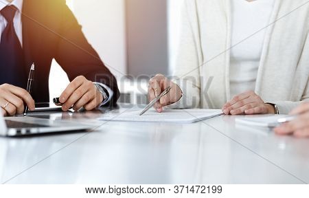 Business People Discussing Contract While Working Together In Sunny Modern Office. Unknown Businessm