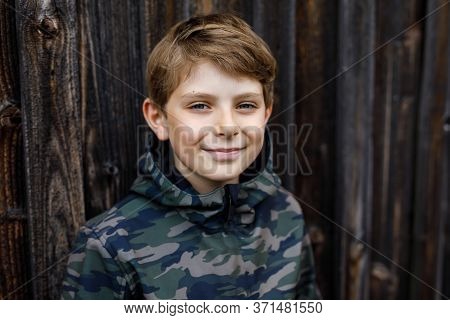 Outdoor Portrait Of Happy Smiling Preteen Kid Boy Wearing Rain Jacket On Rainy Cloudy Day. Handsome 