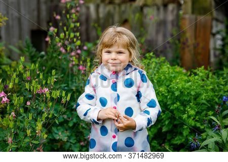 Outdoor Portrait Of Happy Smiling Little Toddler Girl Wearing Rain Jacket On Rainy Cloudy Day. Cute 
