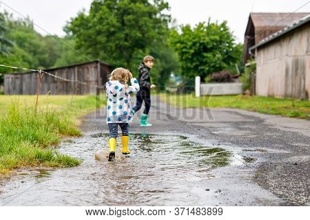 Two Children, Toddler Girl And Kid Boy Wearing Red And Yellow Rain Boots, Walking During Sleet. Happ