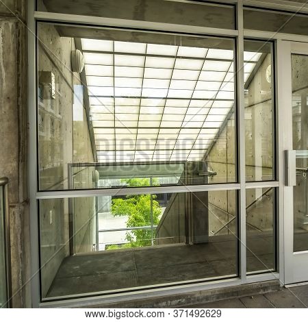Square Glass Door And Wall With View Of Slanted Frosted Roof Over Stairway Of Building