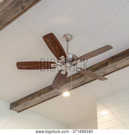 Square Crop Ceiling Fan With Lights Between Decorative Wood Beams Inside Living Room Of Home