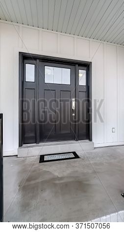 Vertical Frame Home Entrance With Front Porch And Black Front Door Against White Panelled Wall