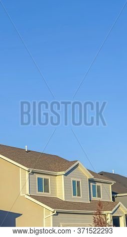 Vertical Homes With Horizontal Wall Sidings And Front Gable Roofs Againts Clear Blue Sky