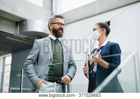 Flight Attendant Talking To Businessman On Airport, Wearing Face Masks.