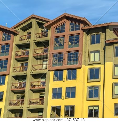 Square Frame Residential Building With Multi Color Wall And Small Balconies Against Blue Sky