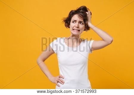 Preoccupied Young Brunette Woman Girl In White T-shirt Posing Isolated On Yellow Orange Wall Backgro