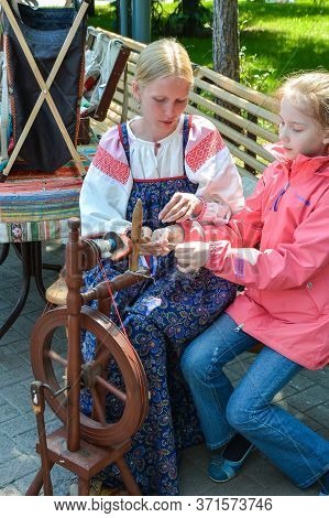 Chelyabinsk Russia June 12 2015 holiday Russia day a woman teaches a girl to work on an old spinning wheel in the Park to remember the traditions