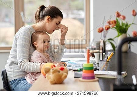 remote job, multi-tasking and family concept - tired mother with baby working at home office