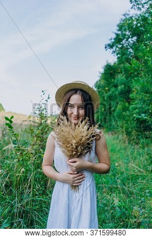 Beautiful Girl In A White Dress With A Bouquet Of Dried Flowers. Young Woman In A Green Park. Girl I