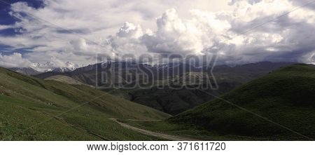 Mountains Above Green Meadows Under A Blue Sky
