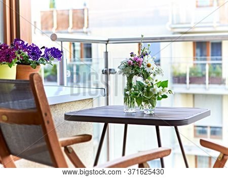 Bouquets of meadow flowers in glass bottles on balkony. Relax zone at home