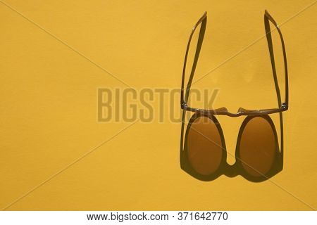 Sunglasses With Long Shadow On A Brignt Summer Yellow Background