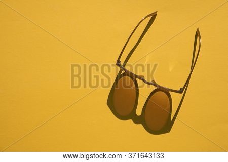 Sunglasses With Long Shadow On A Brignt Summer Yellow Background