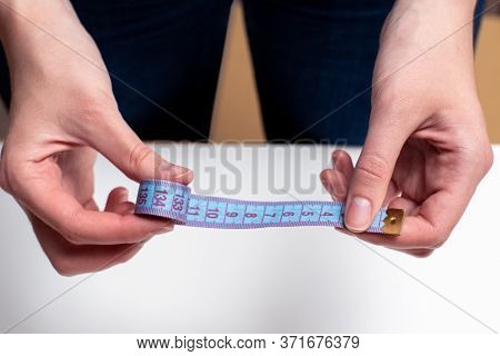 Female Hands Hold Blue Tape Measure, Tape Measure For Measuring Size On A Light Background