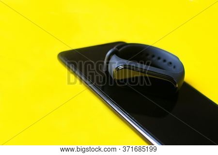 Classic Blue Fitness Tracker And Smartphone On Yellow And Blue Background. Fitness Bracelet For Spor