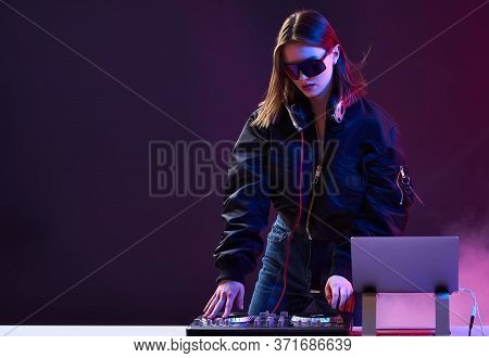 Stylish Dj Girl With Headphones And Glasses On The Bomber Jacket Mixes The Music At The Party And Ne