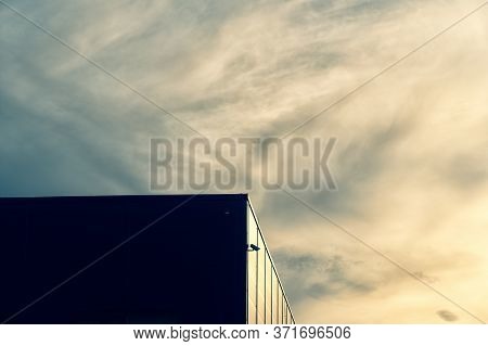 Surveillance Camera On The Facade Of A Modern Building Against The Background Of Clouds. The Evening