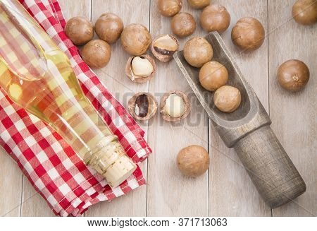 Nuts And Macadamia Oil On Wooden Background - Macadamia Integrifolia