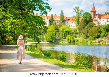 Woman In Hat In Public Park At Spring Season And Looking To Castle Pruhonice In Czech Republic