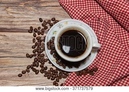 Coffee Cups And Coffee Beans With Red Patterned Fabric On A Wooden Background.