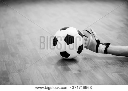 Black And White Image Of Ball In Hands Of Futsal Goalkeeper On Wooden Futsal Floor.
