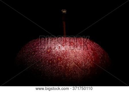Closeup Of A Juicy Red Apple With Waterdrops Against A Black Background