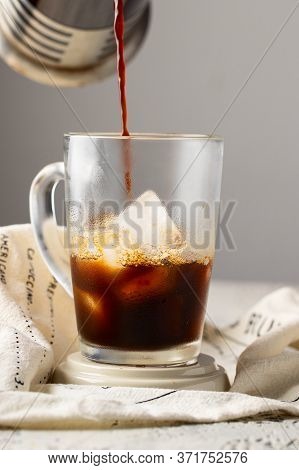 Coffee Pouring Into The Glass Cup With Ice. Ice Coffee Concept.