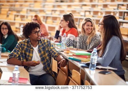 Young freshman students talking and smiling in amphitheater