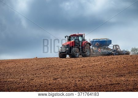 A Modern Tractor Plows The Land In An Agricultural Field
