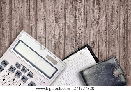Office Flat Lay Composition With Calculator, Address Book And Black Purse On Brown Wooden Table Back