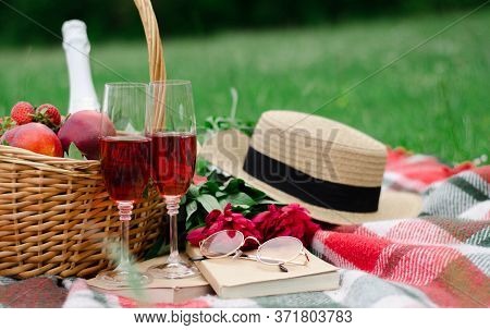 On The Grass There Is A Checkered Plaid And On It Is A Basket With Strawberries, Peaches, In The Gla